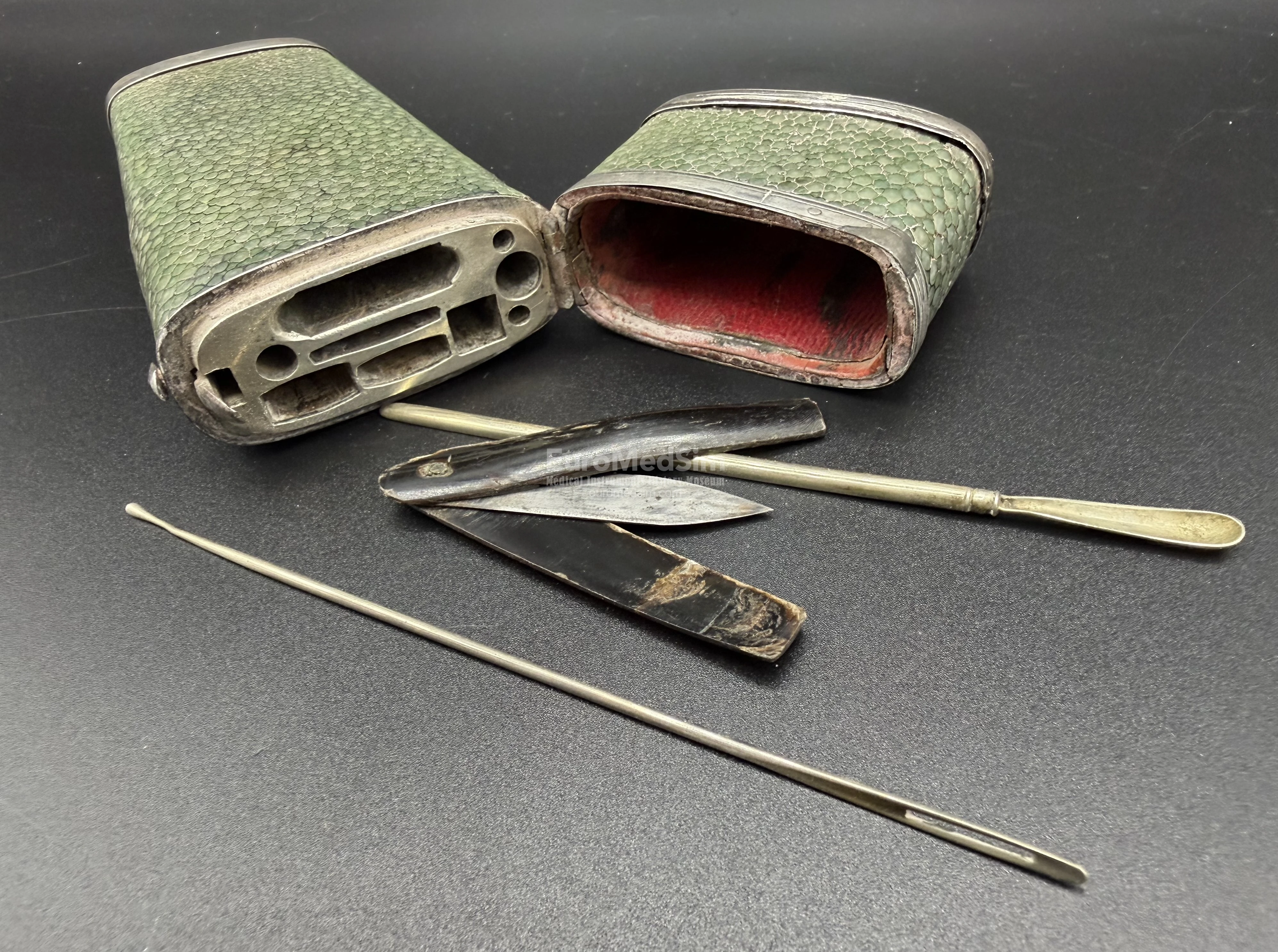 The original content of the case is not presented and etui is filled now with several later instruments: a lancet with handle made of brown horn, a spoon-probe and blunt needle with an eye.  The pocket green-stained shagreen case, English, ca. 1800