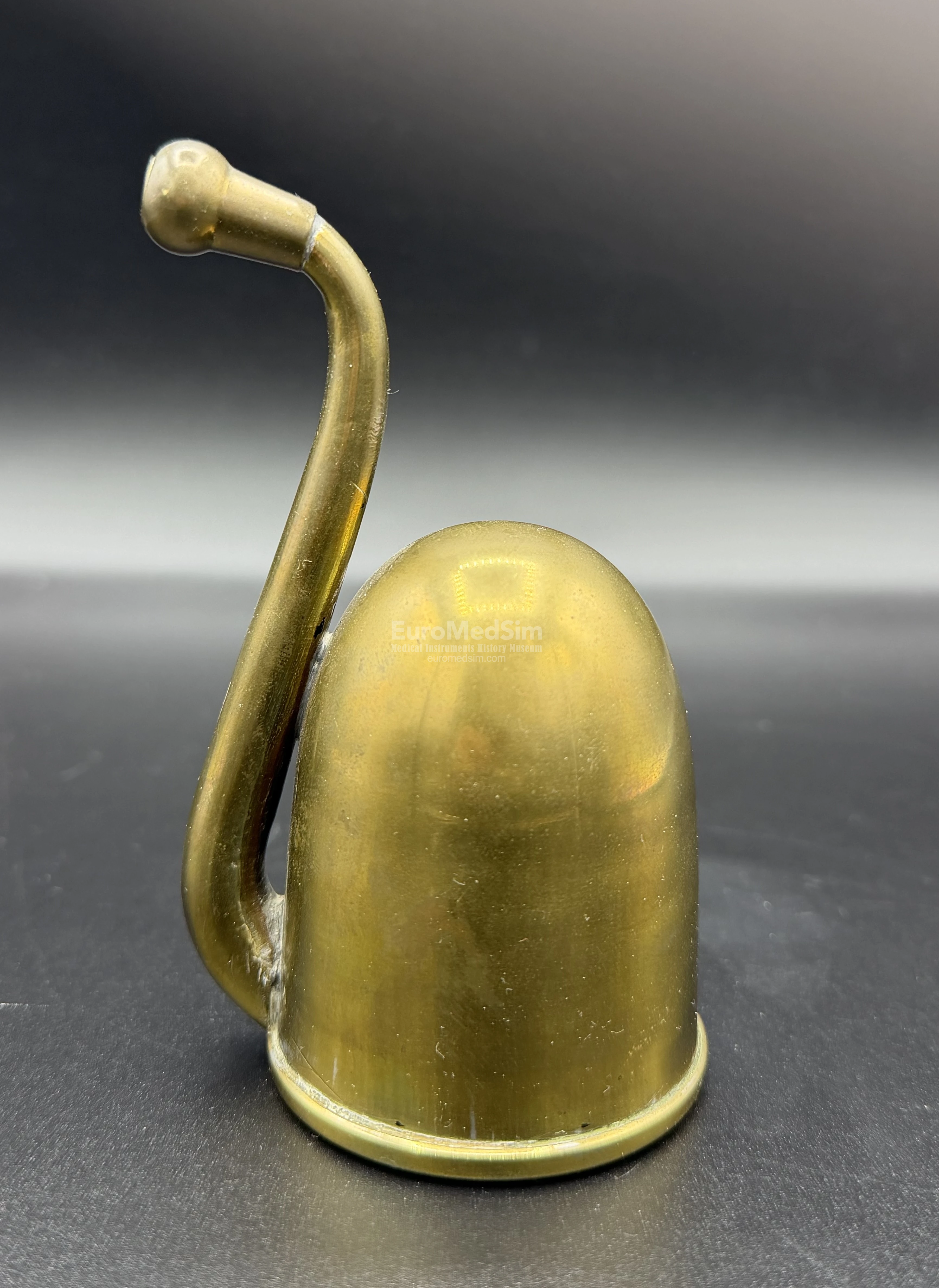 The U-shaped hearing tube extends from the focal point inside the bell, curves outward through the bell's opening, and returns to the ear. This design provides a compact size. England, c. 1880.