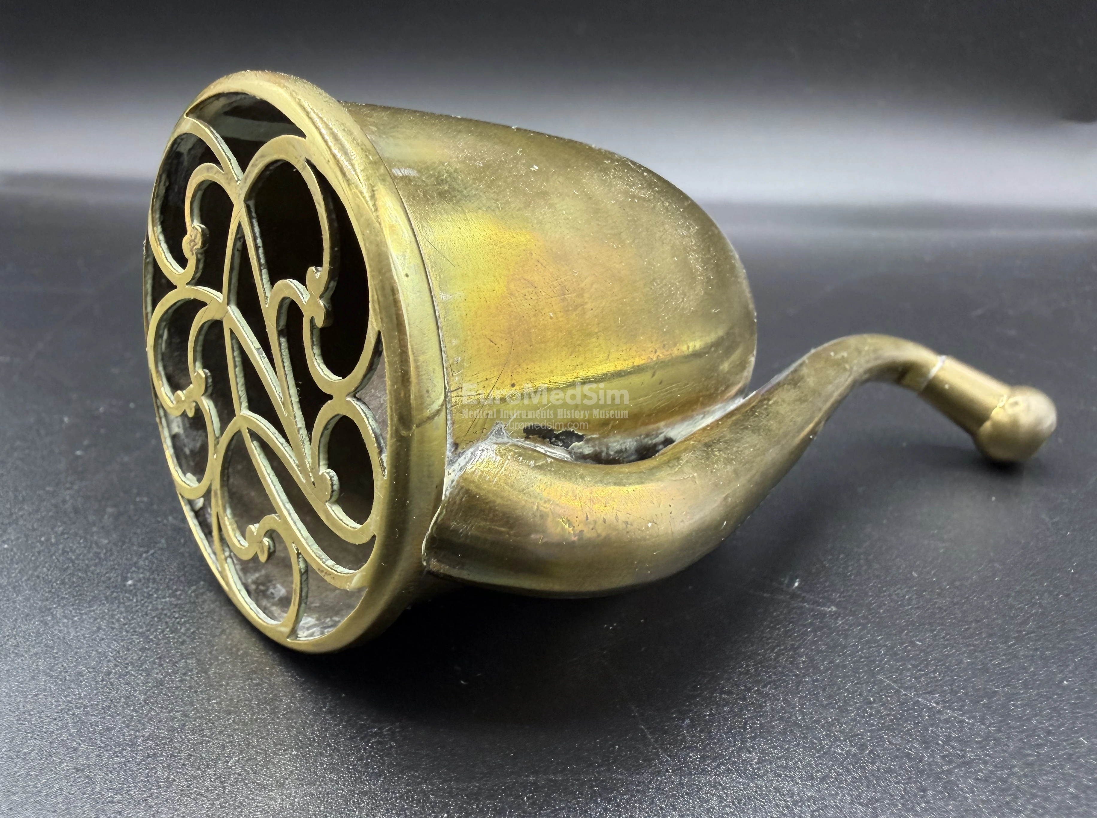 A decorative grille featuring a classic Victorian floral pattern covers and adorns the opening of the sound-collecting bell.