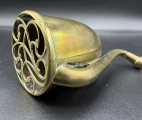 A decorative grille featuring a classic Victorian floral pattern covers and adorns the opening of the sound-collecting bell.