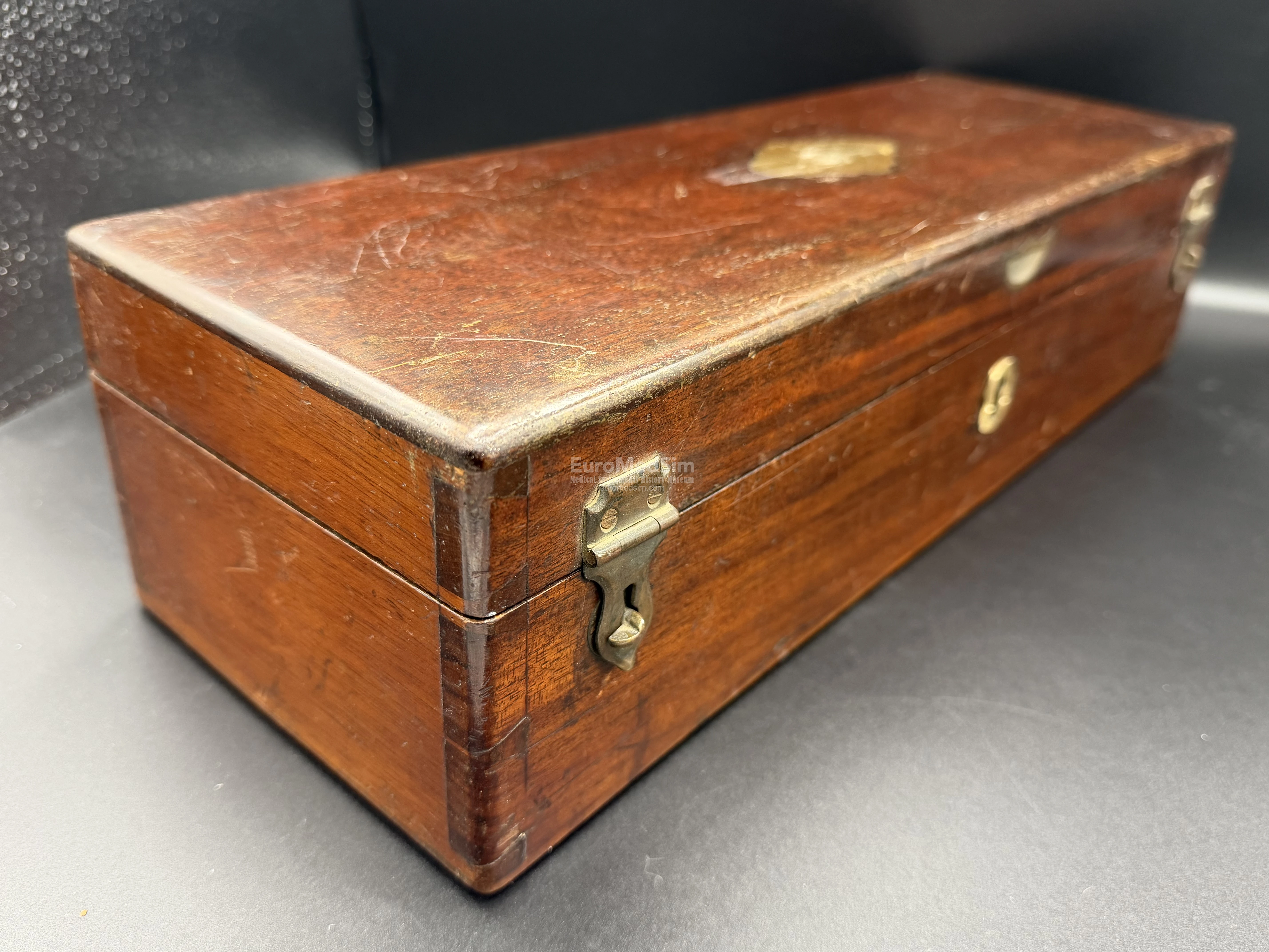 Mahogany box with two fasteners, lock (key available), brass plaque on the upper lead (unsigned), and carrying handle (on the opposite end)